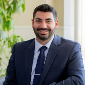 Smiling family dentist in Milwaukee wearing a navy suit in a welcoming office setting.